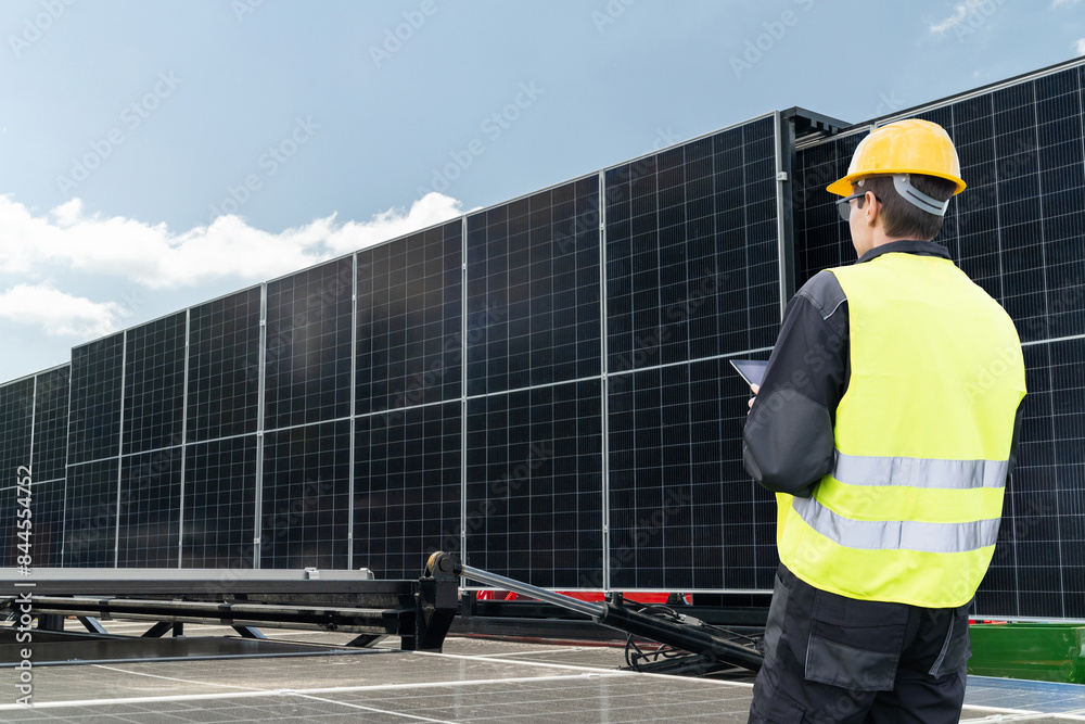 Poster Engineer with tablet computer on a background of mobile solar energy power station..