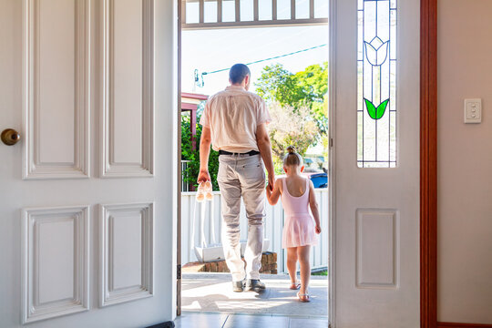 Dad holding young ballet dancers hand as they leave home for dance class