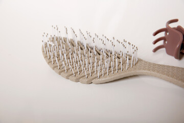 Close up of used hair brush on white table, hair loss and head skin hygiene at home concept
