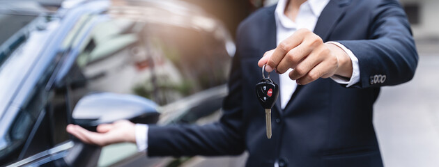 transportation rental automotive business concept. Close up hands of rental auto agent giving car remote key to client to travel sightseeing.