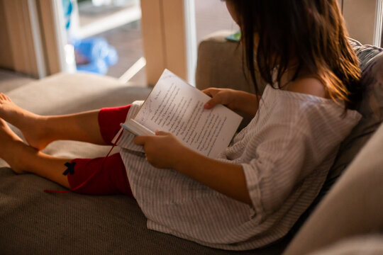 A child sitting on a couch in the living room holding a bedtime storybook