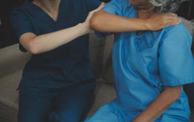 Obraz premium Old woman training with physiotherapist using dumbbells at home. Therapist assisting senior woman with exercises in nursing home. Elderly patient using dumbbells with outstretched arms.