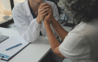 Obraz premium African female doctor hold hand of caucasian woman patient give comfort, express health care sympathy, medical help trust support encourage reassure infertile patient at medical visit, closeup view.