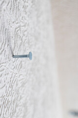 nail driven into white wall close up