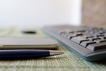 pen, smartphone and keyboard on table close up