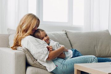 Mother and child bonding on a cozy couch with a coffee table in the background against a white wall