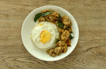 spicy stir fried chicken with mashed dry chili and basil on rice topping egg in plate