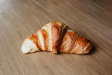Freshly Baked Croissant on Wooden Table. Close-Up View of Flaky Pastry. Croissant