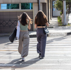 Two girls cross a zebra crossing in the city