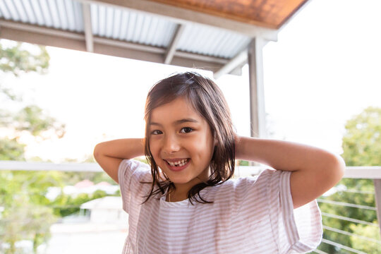 A young girl smiling at the camera with her hands at the back of her head