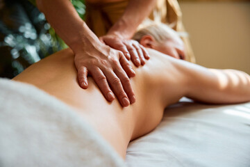 Closeup of masseuse massaging female patient at spa