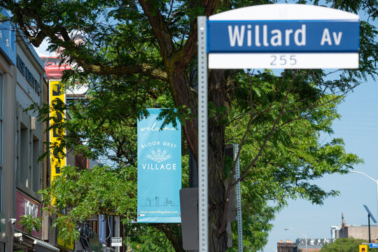 looking east to a Bloor West Village BIA hanging banner sign at Willard Avenue on Bloor St W in Toronto, Canada