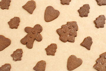 Christmas sweet food geometric pattern, gingerbread cookies, biscuits on baking paper as holiday background. Top view minimal pattern, flat lay from traditional baked different shapes, new year