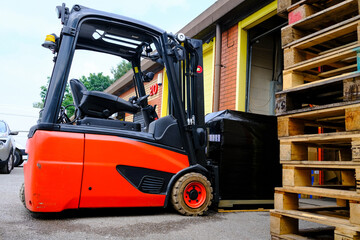 Forklift moving wrapped pallet in warehouse with wooden pallets in foreground