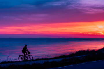 Obraz premium A vibrant photo of a person riding a bicycle along a coastal path at sunset, with the sea and sky in vibrant hues 