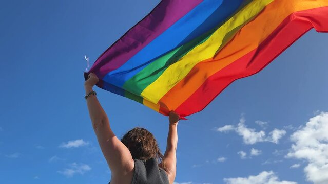 Gay pride parade, woman woman holding flag with rainbow lgbt flags