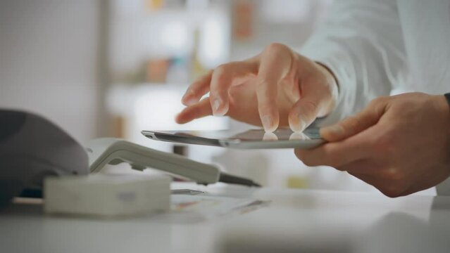 A pharmacist assistant applies their knowledge by operating an electronic device in the pharmacy department. An employee holds a tablet in his hands, checking the expiration date of medications