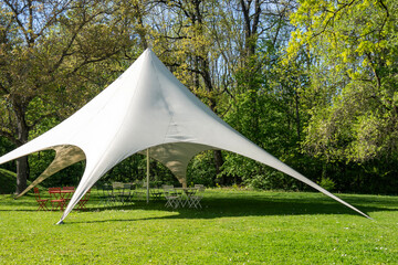 Large white gazebo tent with garden chairs and tables in a park