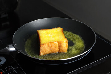 toast slice bread in the pan during bake with organic butter with sugar on electric stove as delicious homemade breakfast butter toast for family members before working in grey modern design kitchen