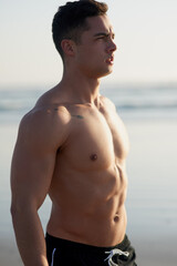 Fitness, morning and man on beach for workout, exercise or training outdoors for surfing by ocean. Nature, athlete and body of confident person by sea for wellness, health and muscle for water sports