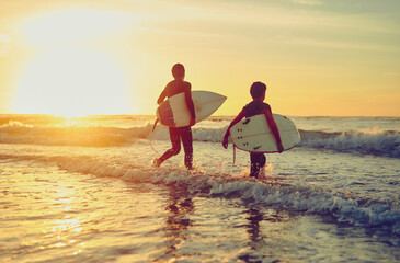 Sunset, beach and children with board to surf on adventure in summer vacation and holiday. Kids,...