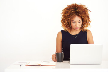 Black woman, laptop and desk with coffee cup in studio by space for mock up with thinking by white background. Person, computer and drink tea with reading, research and notebook at creative agency