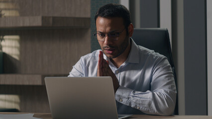 Indian man businessman American investor broker rub hands hoping wish to win lose with laptop at office feel annoyed having problems with computer angry bad result failure data loss password wrong