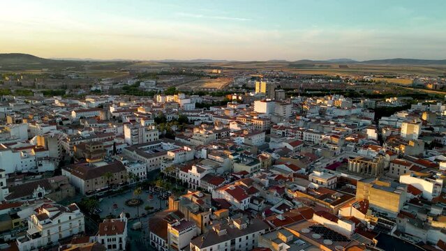 Panoramic aerial view of Spanish city MERIDA at sunset. Drone forward above Spain Square in the old town city. Beautiful sunset colours reflecting on buildings. Travel