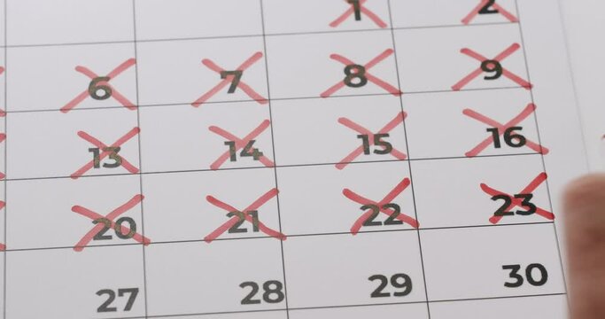 Close-up of calendar with red crosses marking passed days, representing schedule tracking and planning.