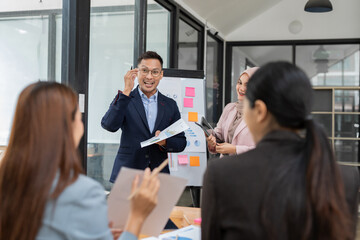 Asian business group discussing graph work at the office..
