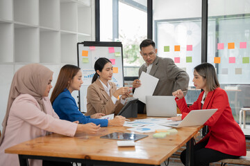Group of Asian businessmen are presenting graphs on a whiteboard.