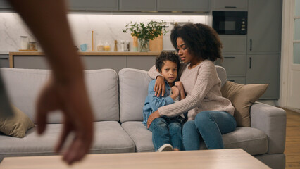 Fototapeta premium Domestic violence African American ethnic family. Aggressive man father threaten beat clenched fist back view scared mother protect frightened little boy child kid suffering physical abuse indoor home