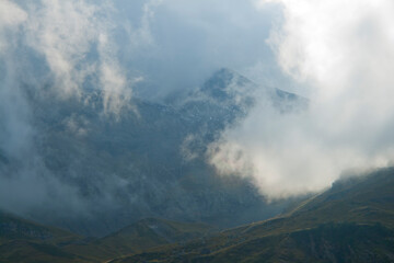 sharp mountain peaks surrounded by wisps of cloud on the summits