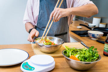 Chef at the kitchen preparing spicy glass noodle salad