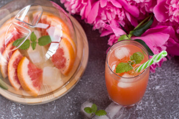Grapefruit drink in a glass with a straw, mint and ice. Refreshing drink, freshly squeezed refreshing juice