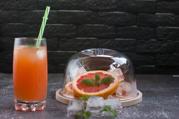 Grapefruit drink in a glass with a straw, mint and ice. Refreshing drink, freshly squeezed refreshing juice