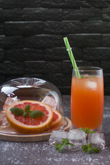 Grapefruit drink in a glass with a straw, mint and ice. Refreshing drink, freshly squeezed refreshing juice