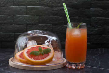 Grapefruit drink in a glass with a straw, mint and ice. Refreshing drink, freshly squeezed refreshing juice