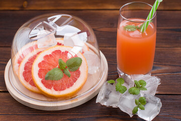 Grapefruit drink in a glass with a straw, mint and ice. Refreshing drink, freshly squeezed refreshing juice