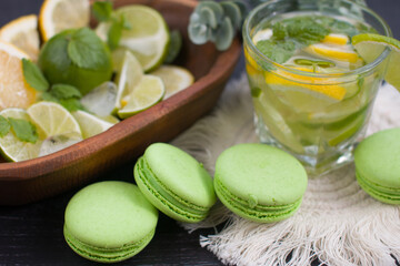 citrus lemon drink with lime in a glass, mint and ice and dessert macaroni cake. Refreshing drink, freshly squeezed refreshing juice