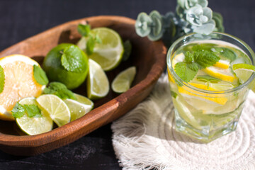 citrus lemon drink with lime in a glass, mint and ice and dessert macaroni cake. Refreshing drink, freshly squeezed refreshing juice