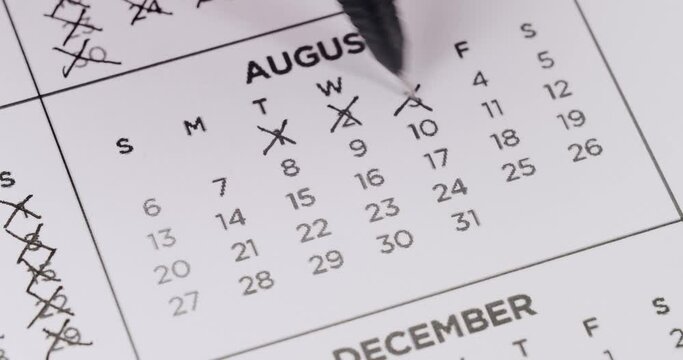 Close-up image of a calendar with a pen marking an important date in August. Concept of planning, scheduling, and time management.