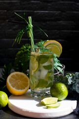 citrus lemon drink with lime in a glass with a straw, mint and ice. Refreshing drink, freshly squeezed refreshing juice