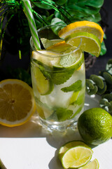 Fototapeta premium citrus lemon drink with lime in a glass with a straw, mint and ice. Refreshing drink, freshly squeezed refreshing juice