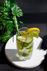 citrus lemon drink with lime in a glass with a straw, mint and ice. Refreshing drink, freshly squeezed refreshing juice