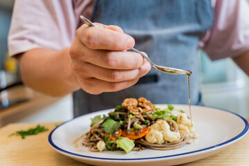 Chef at the kitchen preparing japanese buckwheat pasta with lentils