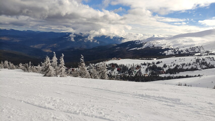 Drahobrat, ski resort, Carpatian mountains. Dramatic winter landscape, gloomy sky over the mountains. Panoramic winter nature. Snowy Carpatians, Ukraine. Mountain view, horizon over land, fir trees. 