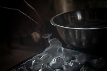 
The chef prepares dessert. The confectioner puts the meringue on a tray. Meringue on a tray

