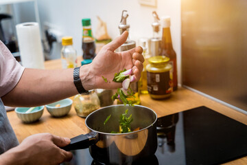 Chef at the kitchen preparing green curry with herbs and rice