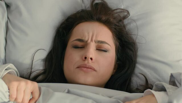 Close up woman unhappy girl female looking duvet blanket open mouth frowning face surprised bed home sleepy lazy peek out dissatisfied expression discomfort morning annoyed displeased asleep bedroom